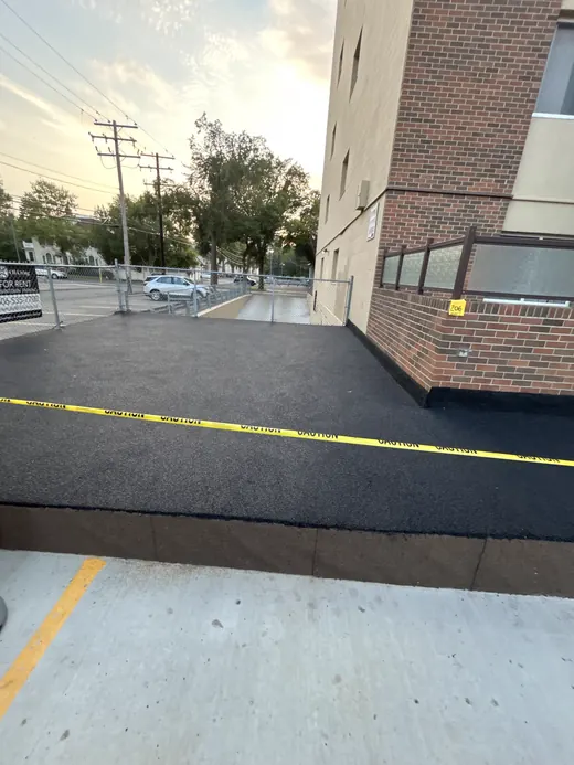 Black rubber resurfaced walkway at an apartment building entrance