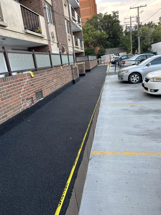 Long black rubber walkway running alongside the apartment block