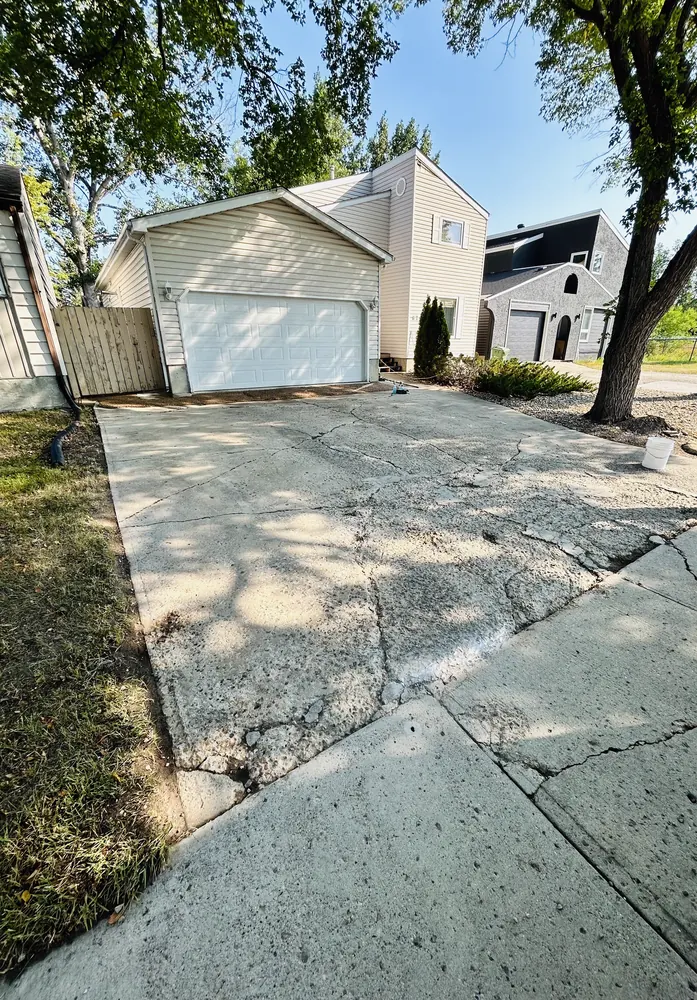 Badly cracked and spalled concrete driveway before rubber resurfacing
