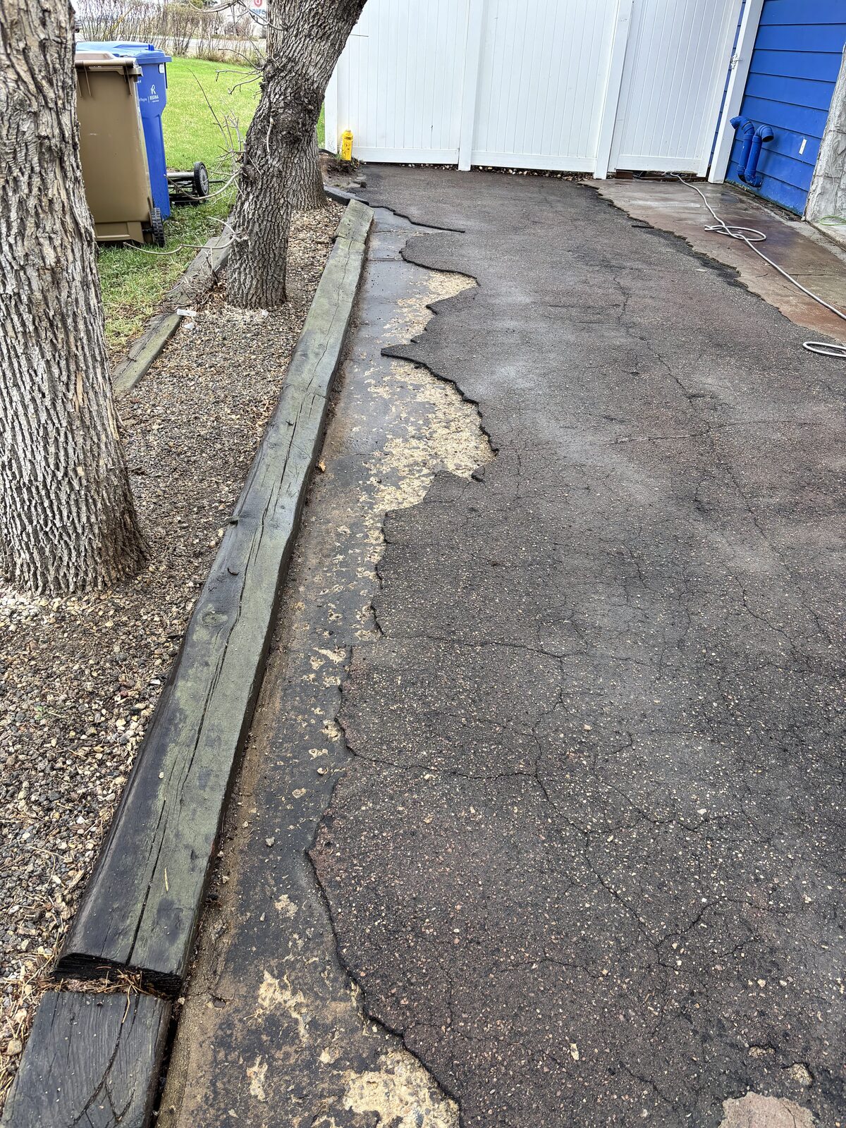Cracked and worn asphalt driveway before rubber resurfacing